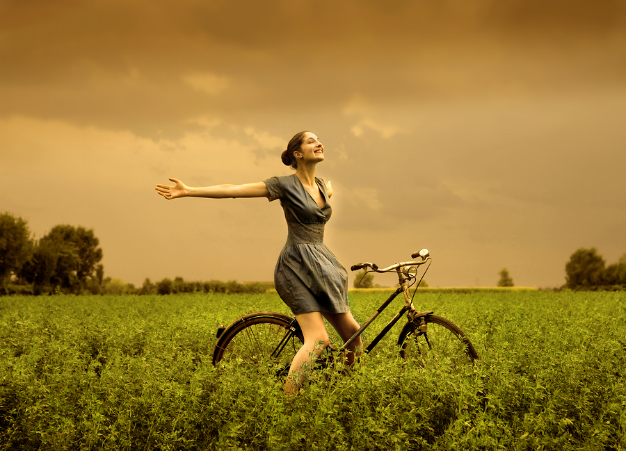 beautiful girl riding bicycle in a grass field