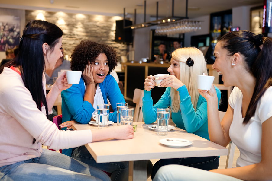 Four female friends enjoying in talking at cafe